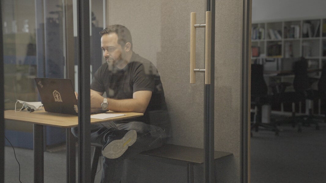 sitzende Person in einer verglasten Box