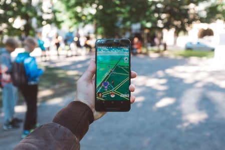Männerhand mit Handy und Pokémon Go Spiel im Park, AR, Mixed Reality