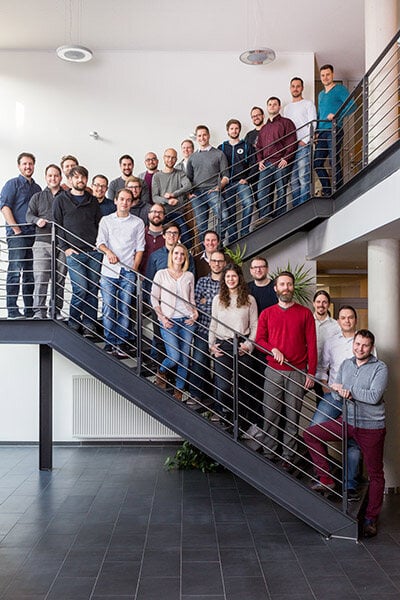 Bürobild von den Mitarbeitenden auf einer Treppe